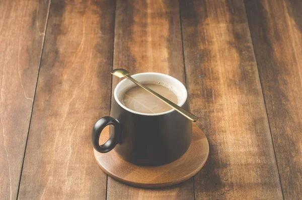 Cangkir Hitam Cappuccino Dengan Sendok Dalam Dukungan Kayu Atas Meja — Stok Foto