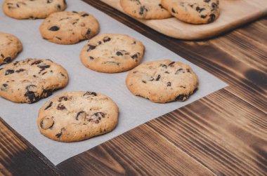 Kabartma kağıdı ve ahşap masa üzerinde çikolatalı kurabiyeler. Kabartma kağıdı ve ahşap masa üzerinde çikolatalı kurabiyeler. Taze hamur işleri.