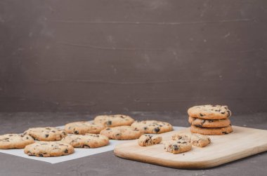 Kabartma kağıdı ve ahşap tahtayla doldurulmuş çikolatalı kurabiyeler. Kabartma kağıdı ve tahta tahtayla doldurulmuş çikolatalı kurabiyeler. Taze hamur işleri. Koyu arkaplan kopyalama alanı. 