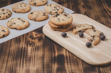 Kabartma kağıdı ve ahşap masa üzerinde çikolatalı kurabiyeler. Kabartma kağıdı ve ahşap masa üzerinde çikolatalı kurabiyeler. Taze hamur işleri.