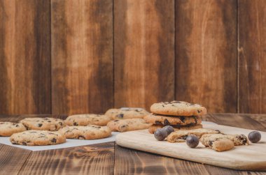 Kabartma kağıdı ve ahşap masa üzerinde çikolatalı kurabiyeler. Kabartma kağıdı ve ahşap masa üzerinde çikolatalı kurabiyeler. Taze hamur işleri. Boşluğu kopyala.