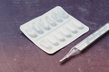 Siyah arkaplan üzerindeki hap paketleri ve termometre / haplar ve termometre siyah arkaplana yerleştirilir.