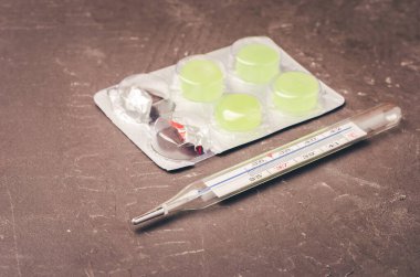 Siyah arkaplan üzerindeki hap paketleri ve termometre / haplar ve termometre siyah arkaplana yerleştirilir.