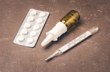 Drug spray bottle, pills packages and thermometer on black background/Drug spray bottle, pills packages and thermometer. Medicine subject. Top view.