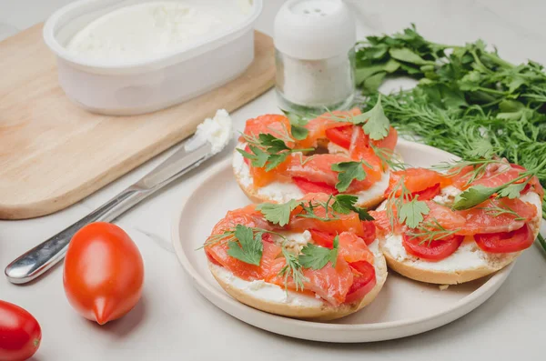 Healthy breakfast with round toast, red fish, vegetables and cheese/cooking of a breakfast with round toast with cheese, red fish, tomatoes and vegetables on a white table.