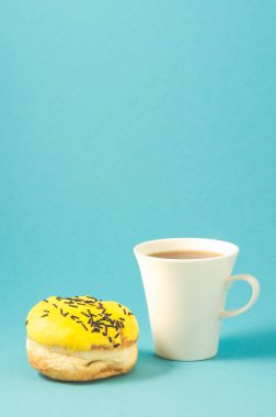 Mavi arka planda çörek ve kahve fincanı. Sarı jöleli donut. Koyu çikolata çubukları ve mavi fincanla süslenmiş.