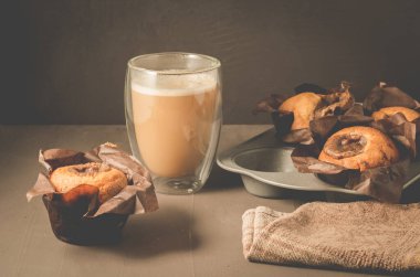 Çikolata dolgulu taze kekler ve kapuçino bardağı / ev yapımı pastalar: koyu arkaplanda çikolatalı dolma ve kapuçino bardaklı kekler