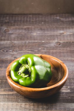 Tahta bir kasede taze yeşil kırmızı biber. Koyu arkaplandaki ahşap kasede taze yeşil biber. Seçici odak