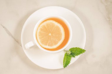 Limonlu çay fincanı ve naneli çay fincanı, beyaz mermer arka planda limon ve nane şekeri.