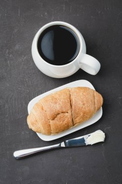Fransız kahvaltısı. Siyah kahve ve siyah taş masada tereyağı bıçağıyla kruvasan. Üst Manzara. Kahve molası.