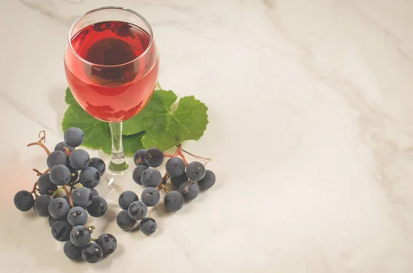 Glass of red wine and grapes/Glass of red wine and grapes on a white marble background , copy space