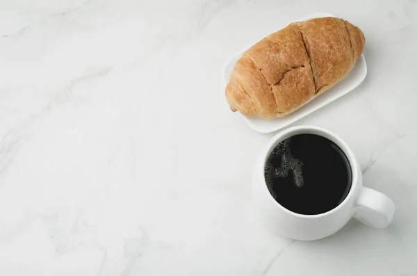 白い石のテーブルの上に黒コーヒーとクロワッサンと白いマグカップ トップビューとコピースペース コーヒーブレイク — ストック写真