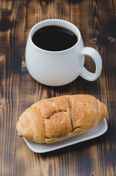木製の背景にブラックコーヒーとクロワッサンとホワイトマグカップ コーヒーブレイク — ストック写真