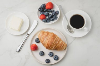Taze kahveyle nefis bir kahvaltı, taze kruvasan ve beyaz bir masada böğürtlen. Üst görünüm. 