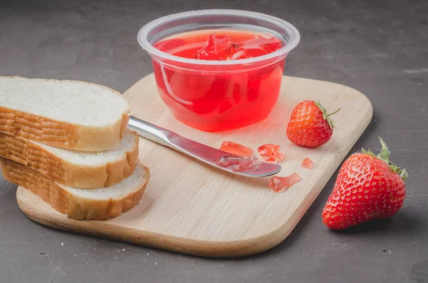 Strawberry jam. Bread and strawberry jam on a wooden table with jar of jam and fresh strawberry. Making sandwiches with strawberry jam.