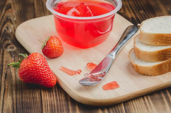 Strawberry jam. Bread and strawberry jam on a wooden table with jar of jam and fresh strawberry. Making sandwiches with strawberry jam.