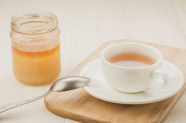 bal/beyaz fincan çay açık bir kavanoz bal bir ahşap tepsi ile açık bir kavanoz ile beyaz fincan da çay. seçici odak