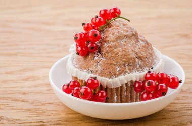 Beyaz tabakta kırmızı üzümlü kek, beyaz tabakta kırmızı frenk üzümü ve ahşap arka planda kırmızı frenk üzümü.