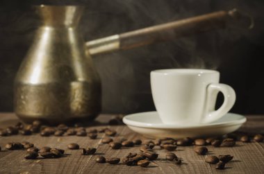 Bakır demlik, sıcak kahve fincanı, bakır demlik ve siyah arka planlı ahşap bir masada sıcak kahve fincanı. seçici odak