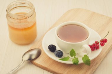 Böğürtlenli çay ve nane ile bir fincan çay ve bal / böğürtlenli çay ve ahşap tepside bir fincan nane ve bal. seçici odak