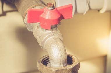 Bir duvardaki kırmızı musluk ve su vanası