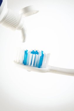 Tüp fırça üzerinde beyaz bir arka plan üzerine sıkılmış diş macunu yakın çekim