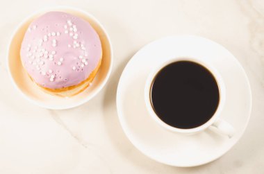 Menekşe jöleli çörek ve beyaz bir masada bir fincan sade kahve. Üst görünüm