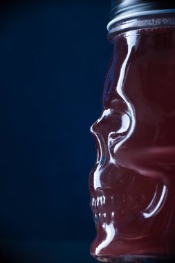 Arka plan olarak mavi ışıkta kafatası şeklinde cam kokteyl.