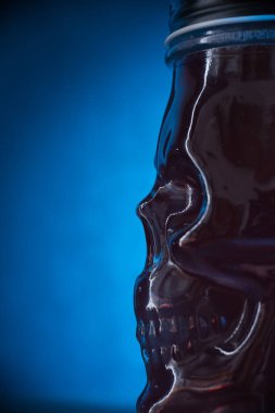 Arka plan olarak mavi ışıkta kafatası şeklinde cam kokteyl.