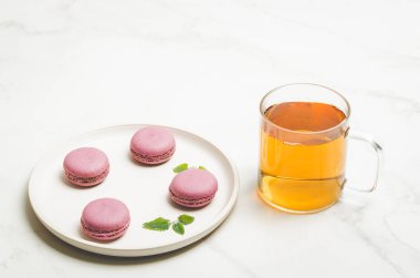 tatlı badem kurabiyesi ya da beyaz bir kasede nane yaprağı ve beyaz arka planda bir bardak çay, Fransız tatlısı.