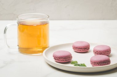 tatlı badem kurabiyesi ya da beyaz bir kasede nane yaprağı ve beyaz arka planda bir bardak çay, Fransız tatlısı.