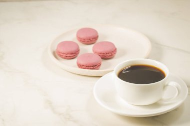 Beyaz bir kasede tatlı badem kurabiyesi ya da badem kurabiyesi ve beyaz arka planda kahve fincanı, seçici bir odak noktası. Fransız tatlısı