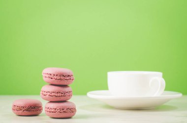 tatlı badem kurabiyesi veya yeşil arka planda beyaz kahve fincanı, seçici odaklı Fransız tatlısı. 