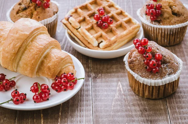 abundance of pastries decorated with red currant/abundance of pastries decorated with red currant on a wooden background. Toned