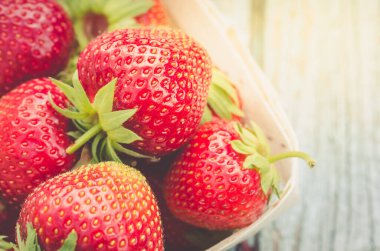Taze çilek ve üstten manzara. Tahta sepetin içinde güneş ışığında taze çilek. Yakın çekim.