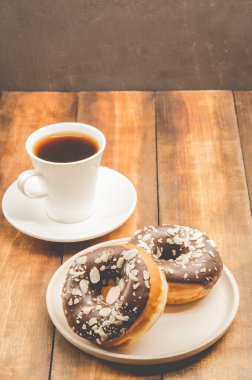 Kahve molası. Sütsüz kahve ve çikolata jöleli bir donat. Ahşap arkaplan.