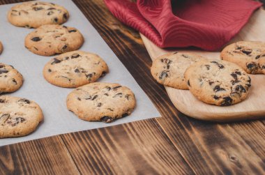 Kabartma kağıdı ve ahşap masa üzerinde çikolatalı kurabiyeler. Kabartma kağıdı ve ahşap masa üzerinde çikolatalı kurabiyeler. Taze hamur işleri.