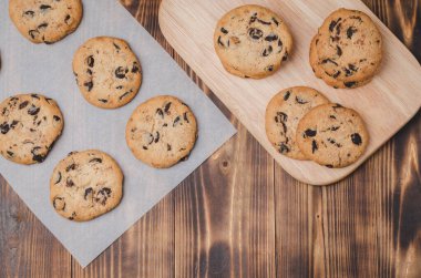 Kabartma kağıdı ve ahşap masa üzerinde çikolatalı kurabiyeler. Kabartma kağıdı ve ahşap masa üzerinde çikolatalı kurabiyeler. Taze hamur işleri. Üst görünüm ve kopyalanma alanı