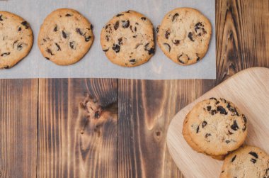 Tahta bir masada çikolatalı kurabiyeler. Taze hamur işleri / Çikolatalı kurabiyeler ahşap bir masada. Taze pastalar. Üst görünüm ve boşluk kopyala.