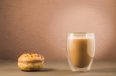 Jöleli çörek ve kapuçino bardağı / jöleli çörek ve kahverengi arka planda kapuçino bardağı.