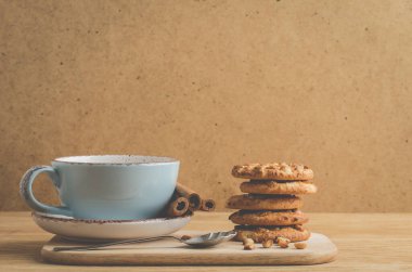 Tarçın çubukları, fındıklı kurabiyeler ve tarçın çubuklu bir fincan kahve / kahvaltı, fındıklı kurabiyeler ve bir fincan kahve.