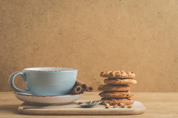 cinnamon sticks, cookies with nuts and a cup of coffee/breakfast with cinnamon sticks, cookies with nuts and a cup of coffee on a wooden tra