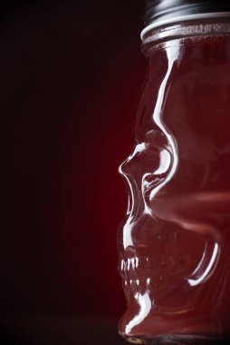 Kırmızı ışık arka planında kafatası şeklinde cam kokteyl.