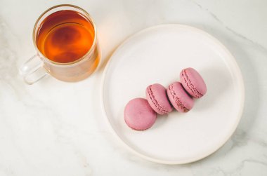 Beyaz arka planda bir bardakta tatlı badem kurabiyesi ya da kurabiye ve çay. Fransız tatlısı 