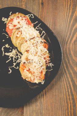 Sebze iliği domateslerinden sebze yahnisi ve siyah kasede peynirle pişirilmiş et.