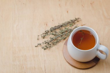 Tahta bir masada beyaz bir fincanda kekik çayı. Yukarıdan görüntüle, metin için boşluk