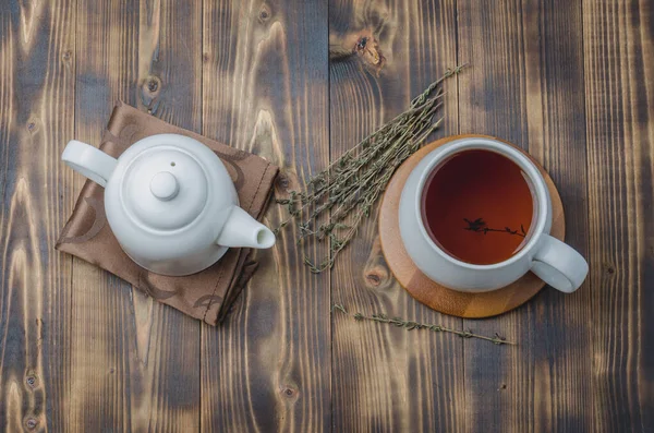 木のテーブルの上にお茶とケトルと白のカップに高い角度から見るタイムハーブティー — ストック写真