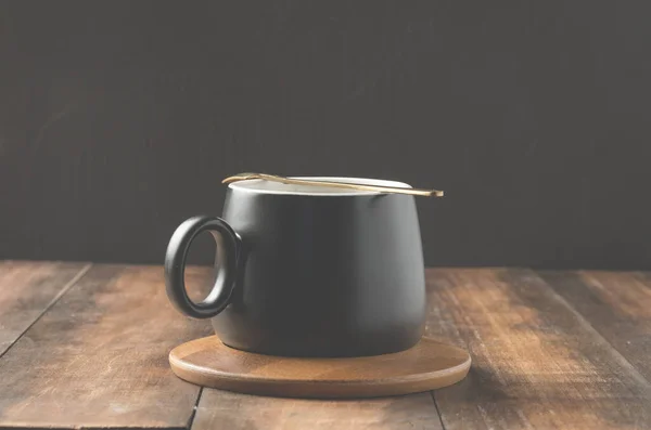 Cangkir Hitam Cappuccino Dengan Sendok Dalam Dukungan Kayu Atas Meja — Stok Foto