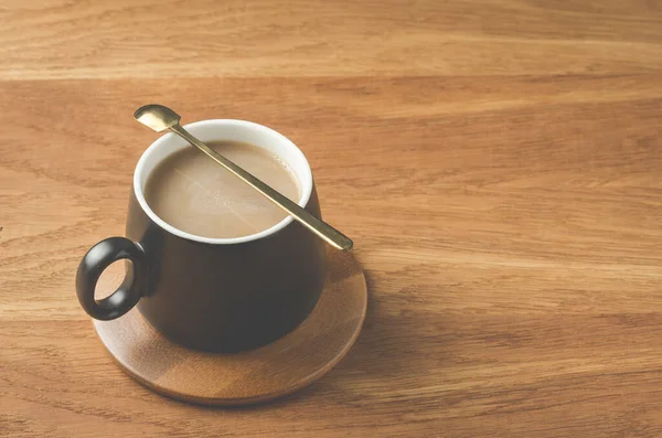 Mug Hitam Cappuccino Dengan Sendok Dalam Dukungan Kayu Atas Meja — Stok Foto