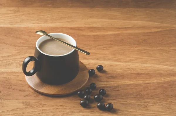 Mug Hitam Cappuccino Dengan Sendok Dalam Dukungan Kayu Dengan Tetes — Stok Foto